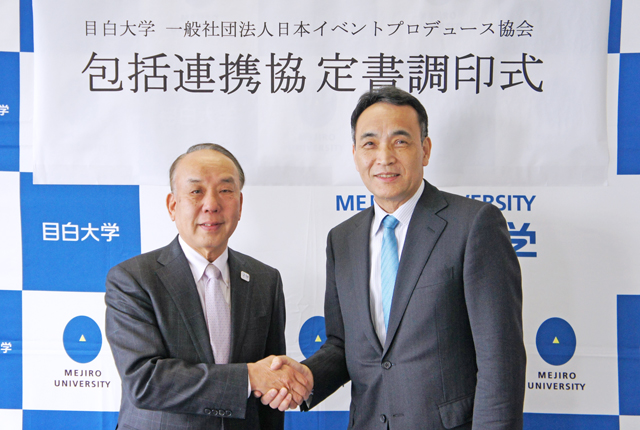 調印式で、握手を交わす佐藤学長(右)と松平輝夫理事長