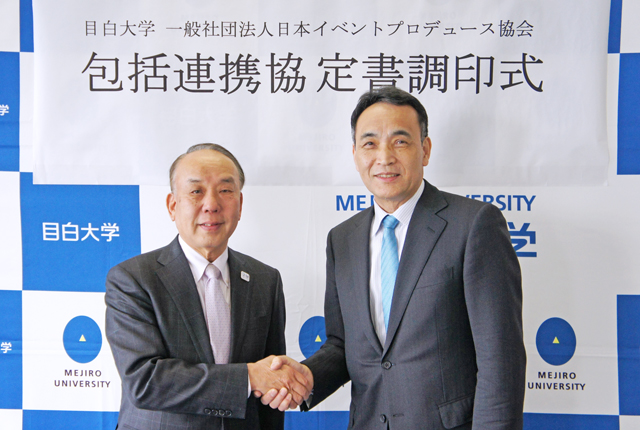 調印式で、握手を交わす佐藤学長（右）と松平輝夫理事長